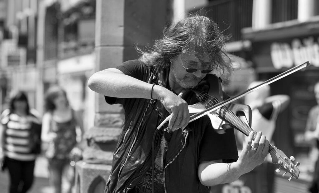 This is a black and white photo of a man playing a musical instrument n Chester and was taken on a Welshot Photographic Academy event - Learn Your Camera, Creative Photography Day shooting at F1.8