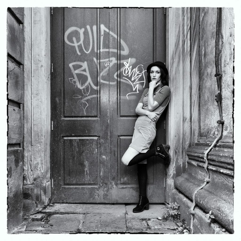 Black and White Photograph of Young Girl in a Doorway with Graffiti and taken at a Welshot Photographic Academy Workshop to Learn about Off Camera Flash for Beginners