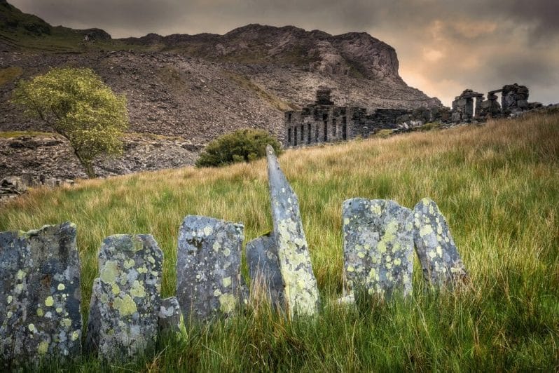 Walking with Your Camera Photographic Workshop from Welshot and Team Leader Helen Iles - Photo is of old slate fences with ruins of the quarry-mans cottages in the background high in the mountains of the Snowdonia National Park