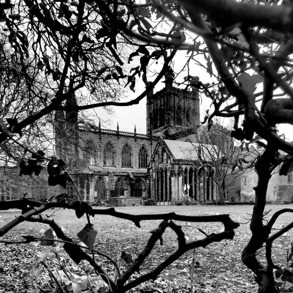 Black and white photo of Chester Cathedral through the trees.