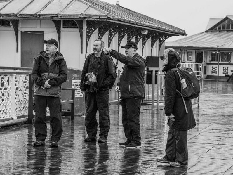 Black and White Photo of Eifion Williams from the Welshot Photographic Academy pointing out some of the landmarks from the Llandudno Pier in North Wales