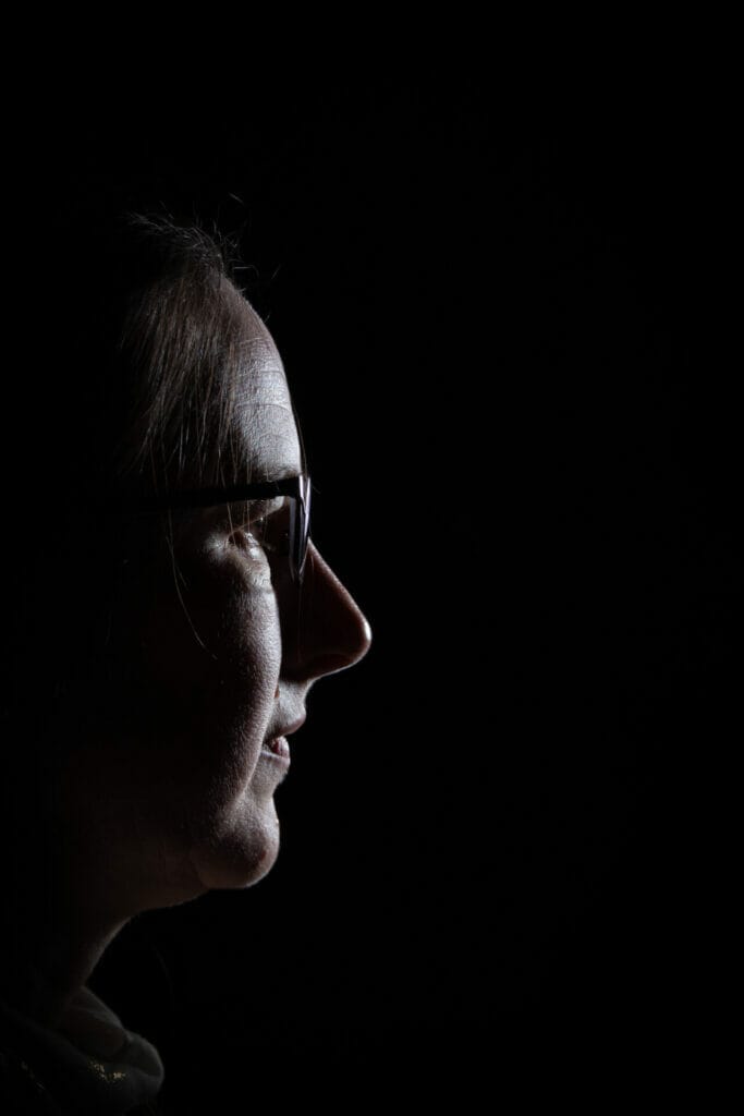 Black and white side portrait photo of a woman having her photo taken in the Welshot Photographic Academy Lighting Workshop in Llandudno