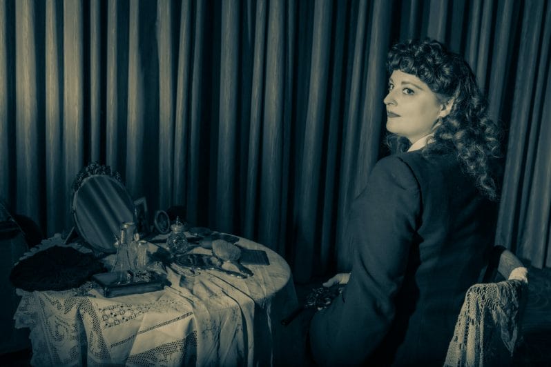Themed Photo-Shoot: Film Noir Photography with Welshot - Black and White Photo of Woman sitting at a bedroom table getting ready to go out