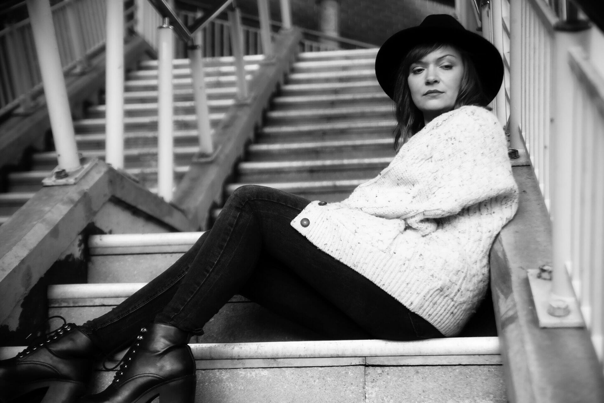 Winter Fashion in Liverpool - Off Camera Flash Photography - Black and White Photo of a Girl wearing a hat and Winter clothing siting on steps
