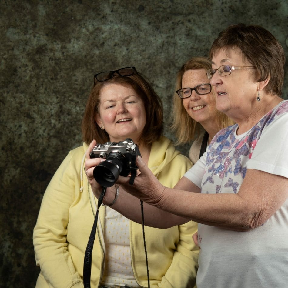 How Moving To Olympus Could Help You With Your Photography - Photo showing three ladies looking at the back of a screen on an Olympus camera in the Welshot Photographic Creative Hub