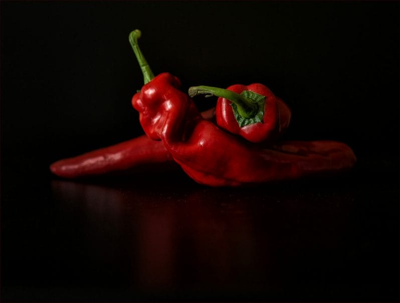 Photograph of two red peppers on a black background - taken at a Food Styling & Photography – Anglesey Photographic Academy Evening