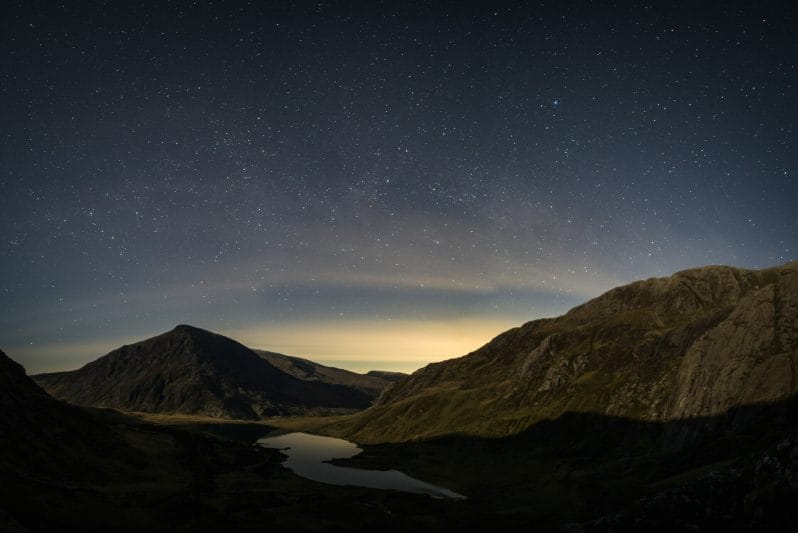 Photo of the night sky over a lake surrounded by mountains - Astro Photography - How To Shoot the Night Sky – Cwm Idwal Snowdonia – Mini Module with Masterclass