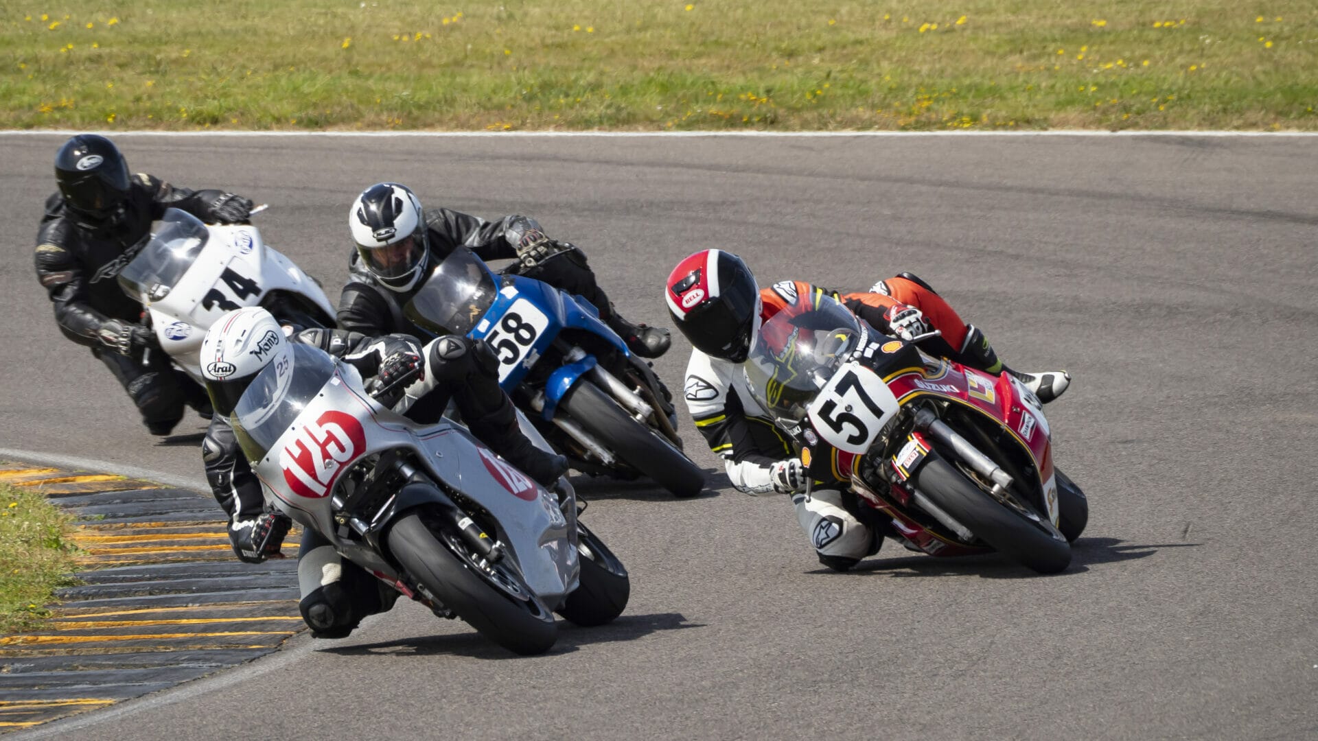 Photo of 4 motorbikes racing around a corner - Action Photography - Classic Bike Racing